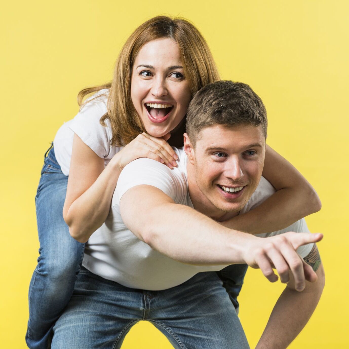man-giving-her-laughing-girlfriend-piggyback-ride-pointing-camera-against-yellow-background-1378x1378.jpg