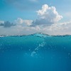 „Kristallklares, tiefblaues Meerwasser mit sanfter Wellenbewegung unter einem weiten, leicht bewölkten kretischen Himmel. Das