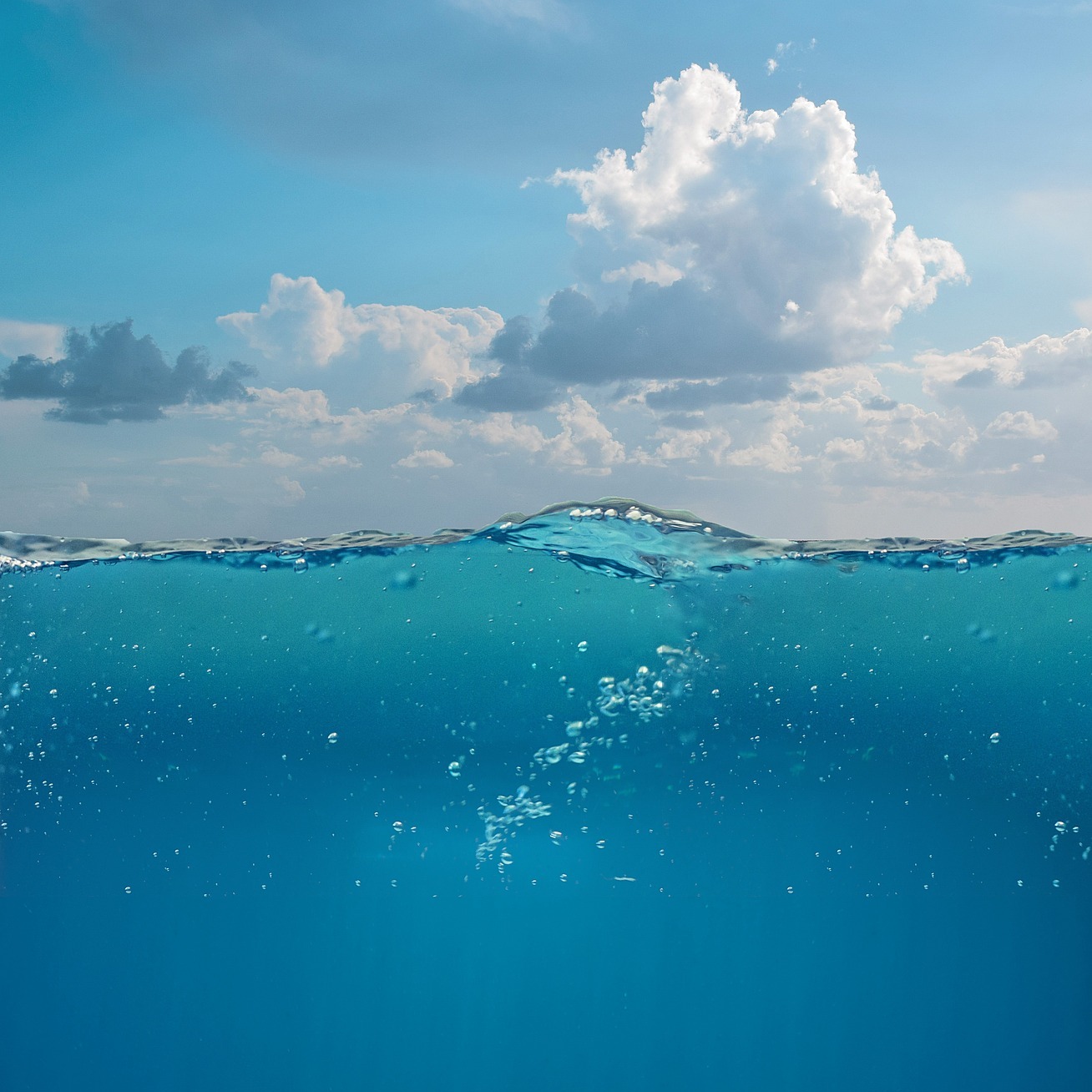 „Kristallklares, tiefblaues Meerwasser mit sanfter Wellenbewegung unter einem weiten, leicht bewölkten kretischen Himmel. Das