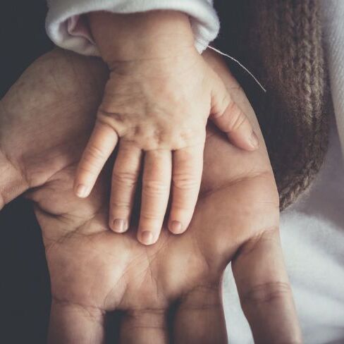 Hand eines Kleinkindes in Elternhand