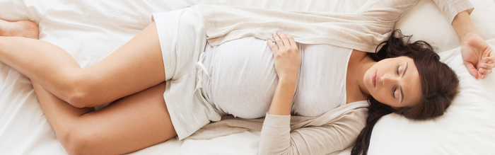 schwangere Frau liegt mit traurigem Blick im Bett