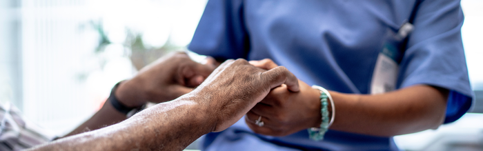 Krankenschwester hält die Hände eines Patienten