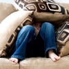 Ein Kind, dass sich auf dem Sofa mit Kissen eine Höhle gebaut hat. 