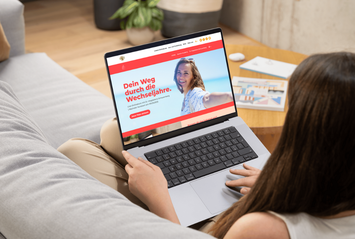 Frau mit Laptop der die Landingpage des Onlinekurses zeigt. 