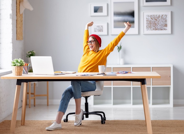 Eine Frau sitz am Laptop und streckt sich.