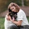 „Eine hochemotionale Nahaufnahme einer jungen Frau mit geschlossenen Augen, die einen großen, dunkel gezeichneten Akita-Hund 