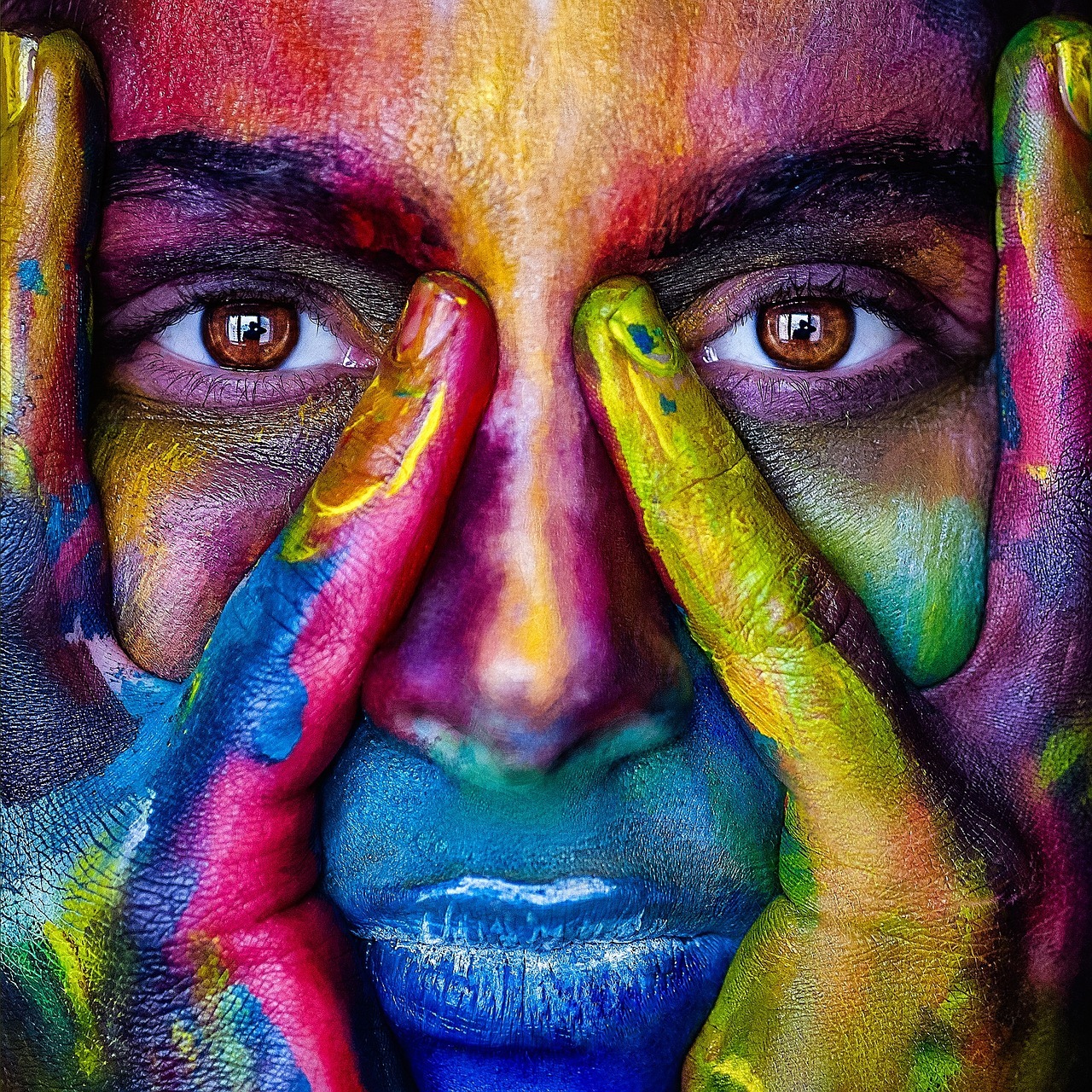 Frau mit Händen im Gesicht, Augen, Nase, mUnd liegen frei. Stärke ausdrückend, bunt mit Farbe bedeckt